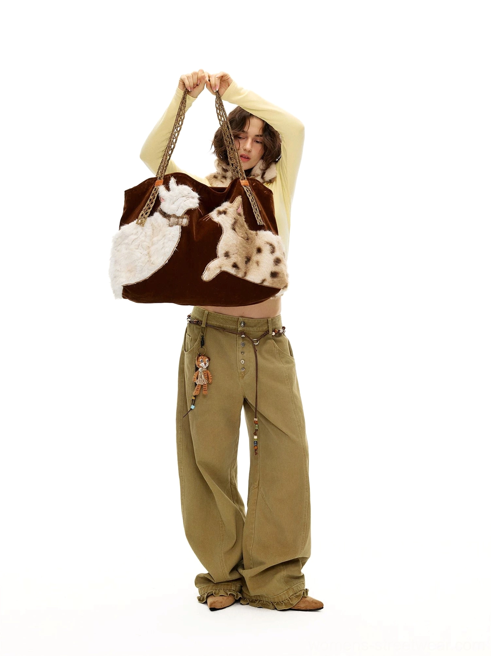 Velvet cat plush tote bag held overhead with braided straps, tassel charm, and dual cat appliques in a Y2K outfit