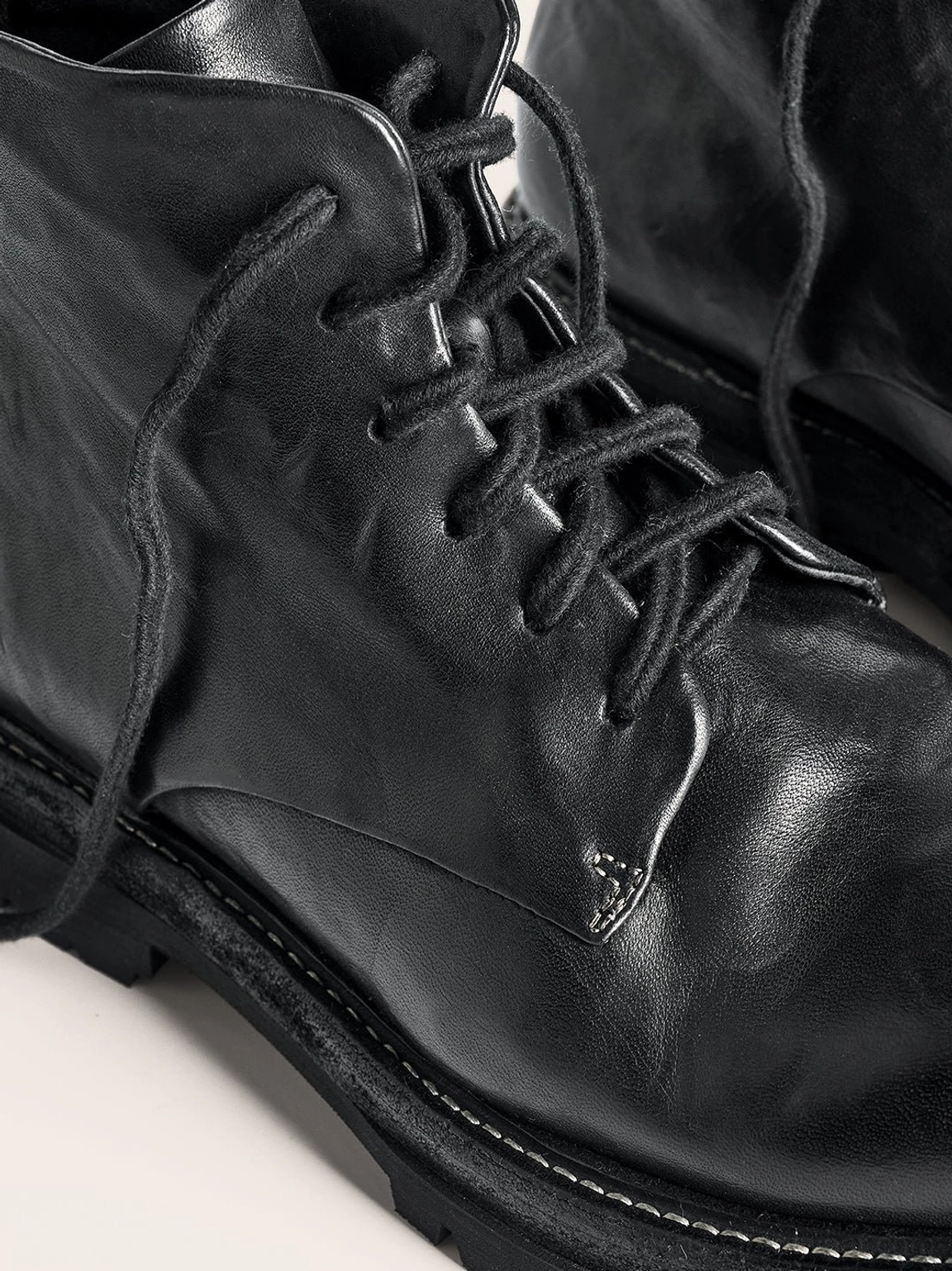 Vintage black washed horsehide rear-zip combat boots with lace-up front, round toe, rugged outsole, and refined utility design