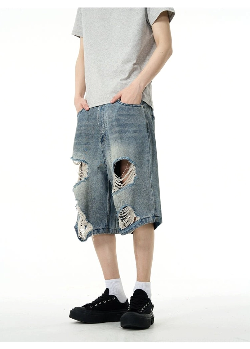 Rear view of vintage washed blue oversized ripped denim Bermuda shorts with relaxed wide-leg knee-length fit