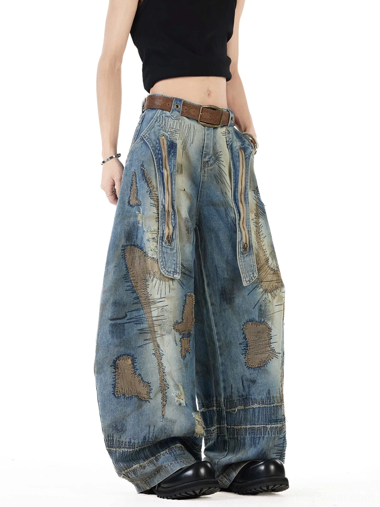 Front three quarter view of vintage blue patchwork balloon jeans with distressed embroidery, oversized utility pockets, ultra wide legs, faded denim wash, and frayed streetwear details