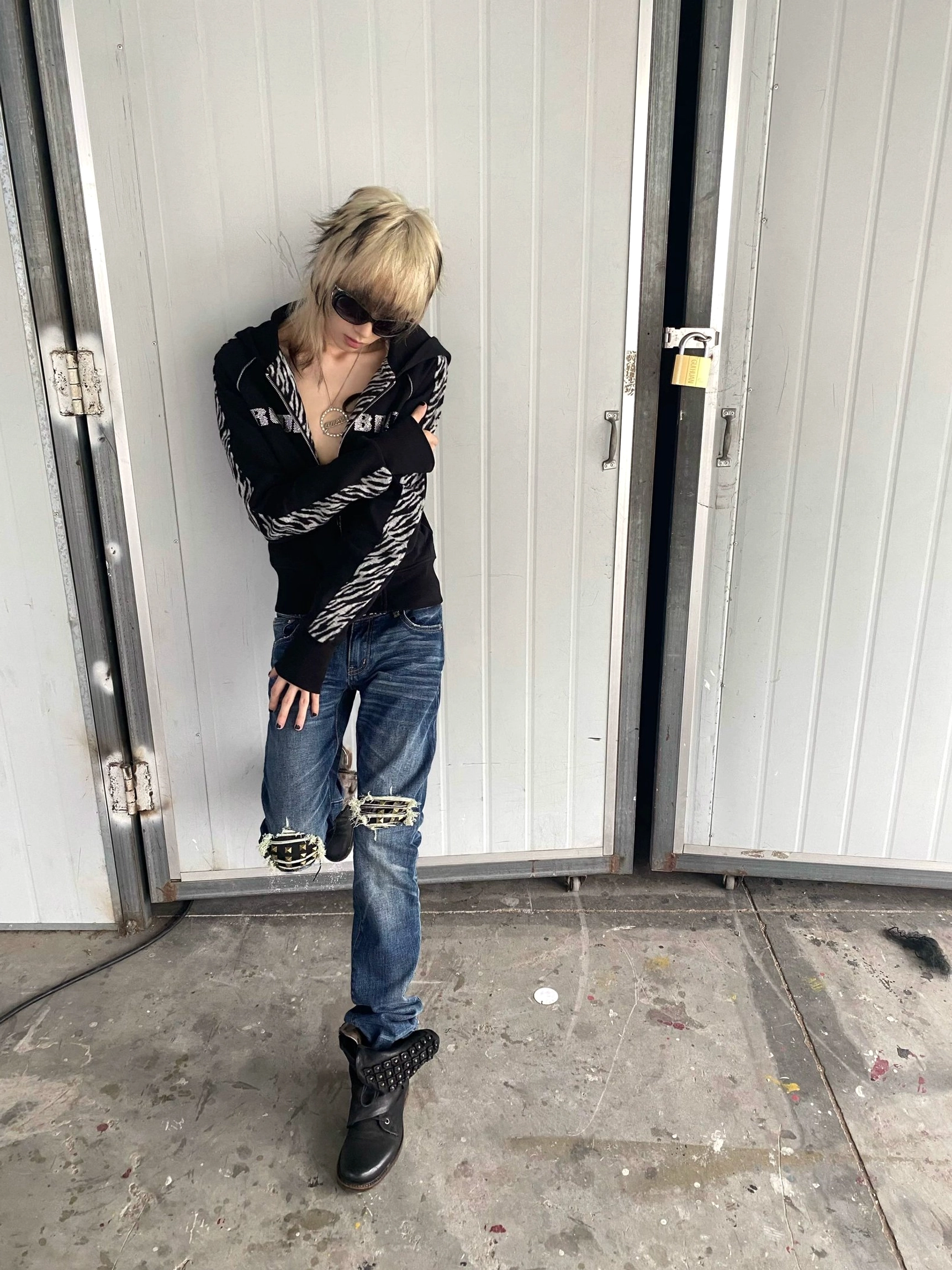 Vintage dark blue slim-fit ripped jeans with layered knee cutouts and patch details styled with black combat boots