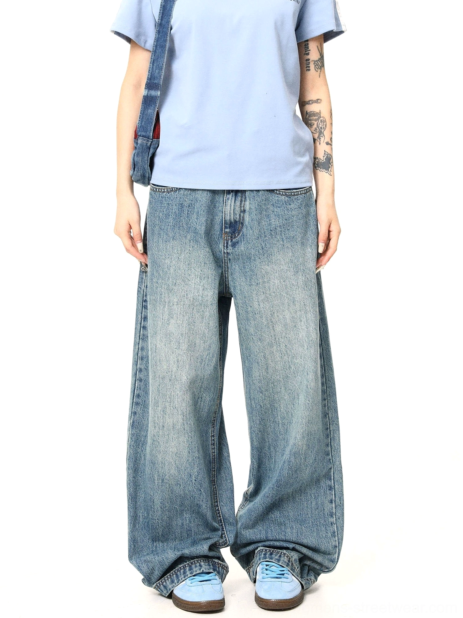 Front view of vintage blue washed wide-leg jeans styled with a light blue T-shirt, blue sneakers, and a denim shoulder bag