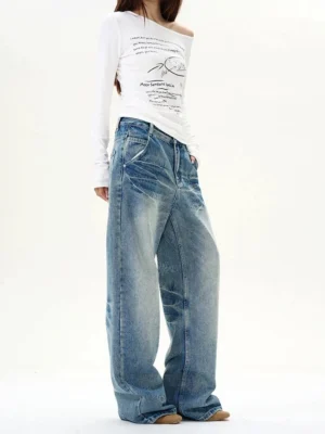 Female model showing the side profile of relaxed baggy vintage blue wide-leg denim jeans with faded distressed wash