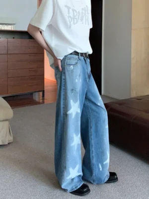Side view of washed blue wide-leg star print denim jeans with faded distressed streetwear details