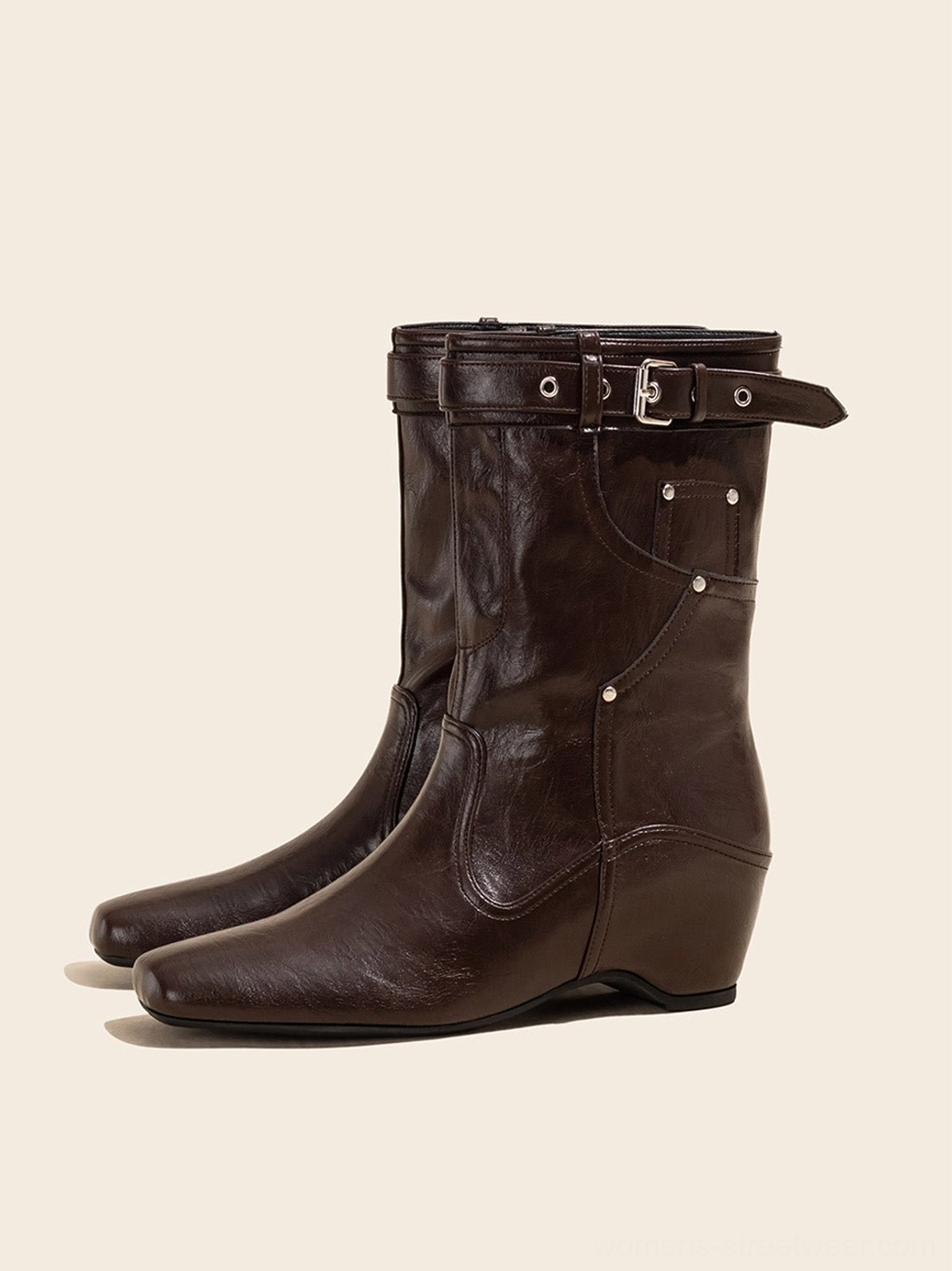 Pair of vintage brown buckle-cuff western ankle boots with low wedge heels on light neutral background