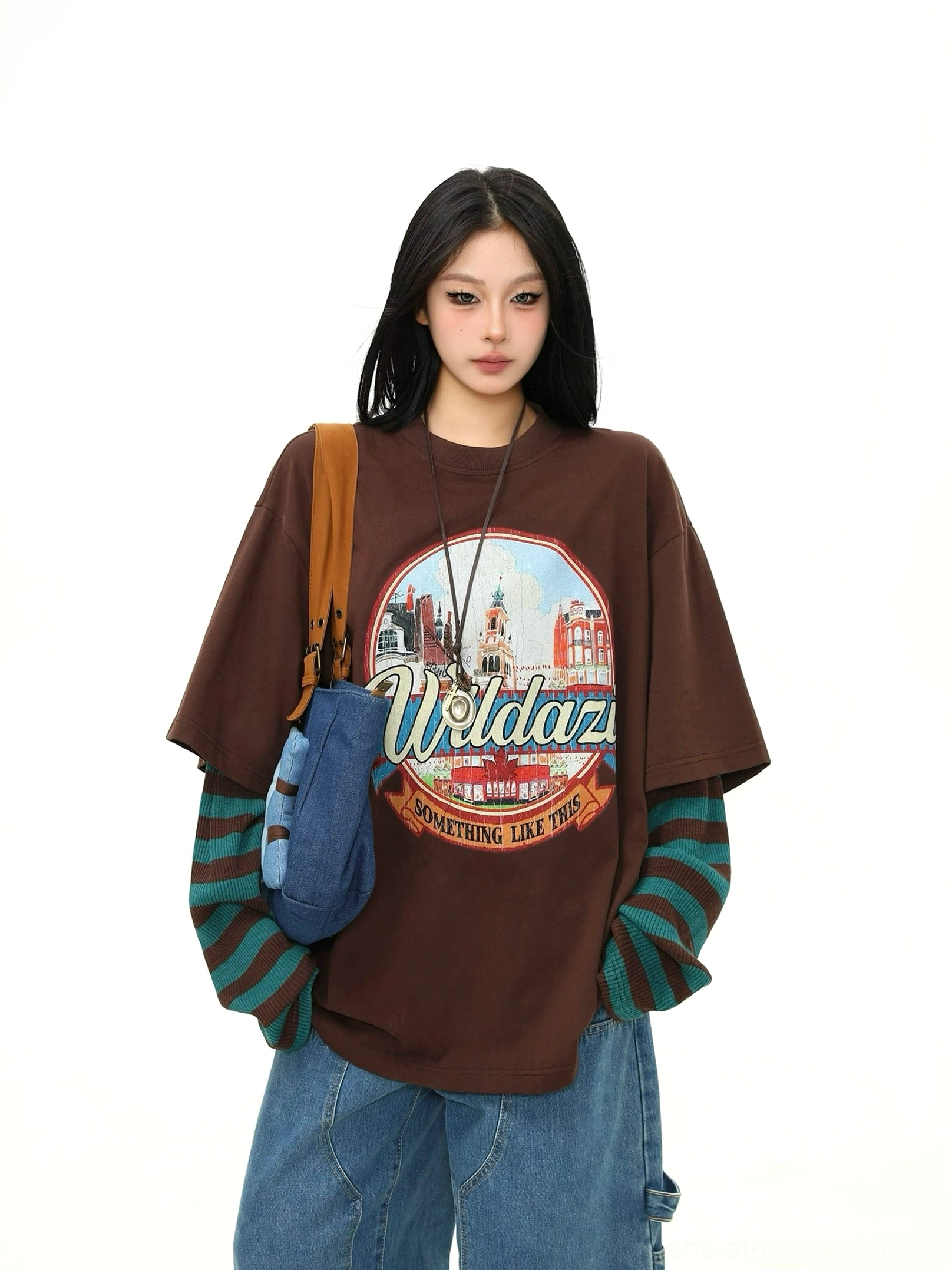 Front view of an oversized brown vintage cityscape graphic T-shirt with built-in green striped long sleeves styled as relaxed women's streetwear