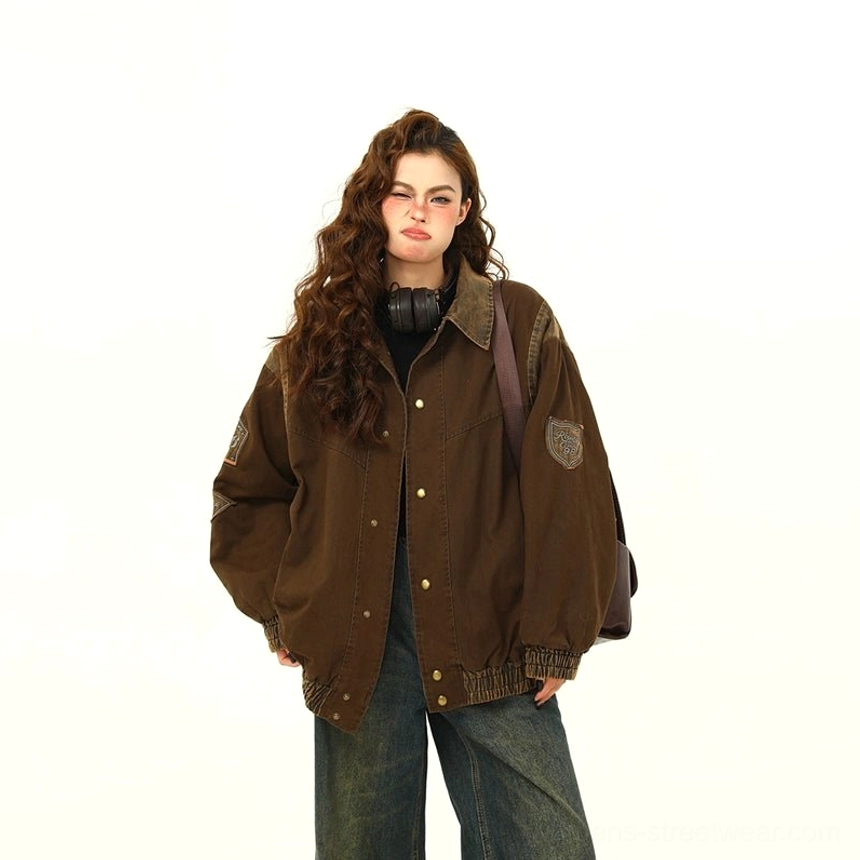 Right three-quarter front view of a vintage brown oversized varsity jacket with embroidered sleeve badge, lapel collar, snap buttons, elasticated hem, and washed texture