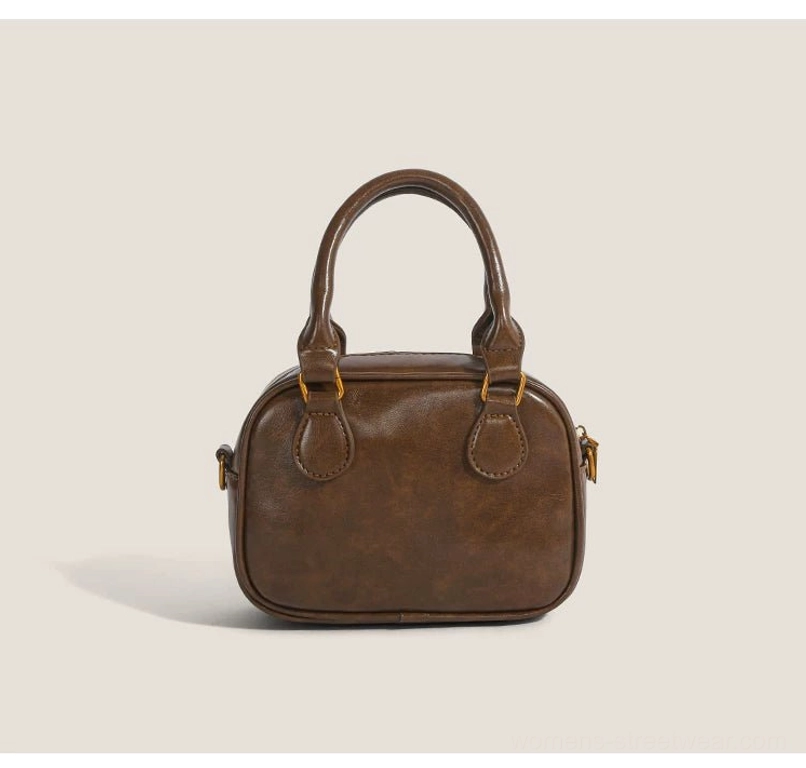Rear view of vintage brown mini satchel crossbody bag with smooth PU finish and gold-tone side lock hardware