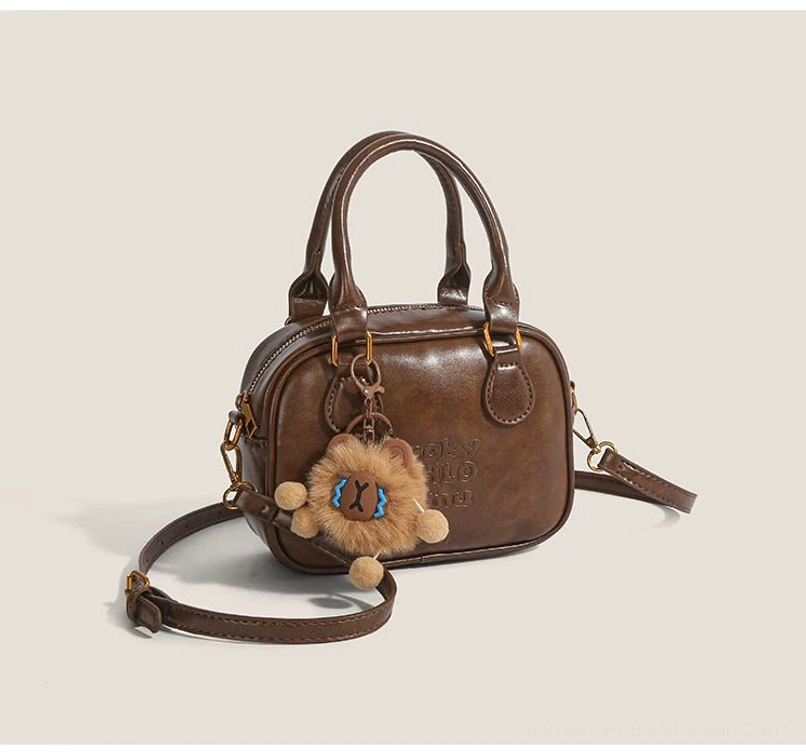 Vintage brown cub charm mini satchel crossbody bag with embossed front lettering, gold hardware and plush charm front view
