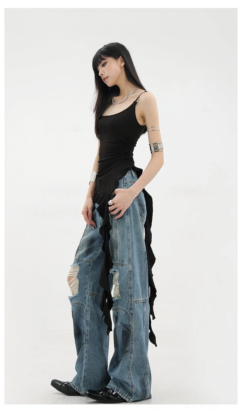 Vintage distressed wide-leg jeans front right three-quarter view on female model with black asymmetric camisole knee ripped details dirt-dyed faded blue wash wide leg silhouette matching top drapery
