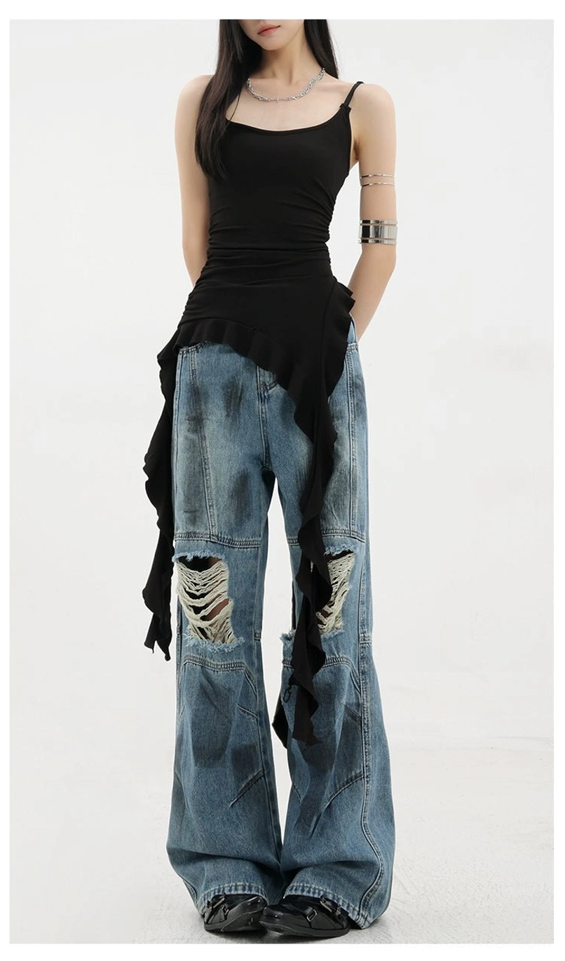 Vintage distressed wide-leg jeans low front view on female model paired with black asymmetric camisole showing front knee ripped cuts faded blue denim wash relaxed wide leg silhouette stacking effect