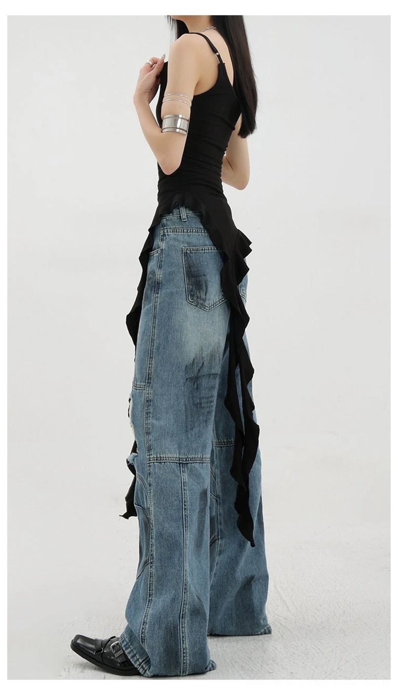 Vintage distressed wide-leg jeans right side full rear view on female model wearing black asymmetric camisole displaying faded blue denim texture loose wide leg cut paneled stitching side drapery details