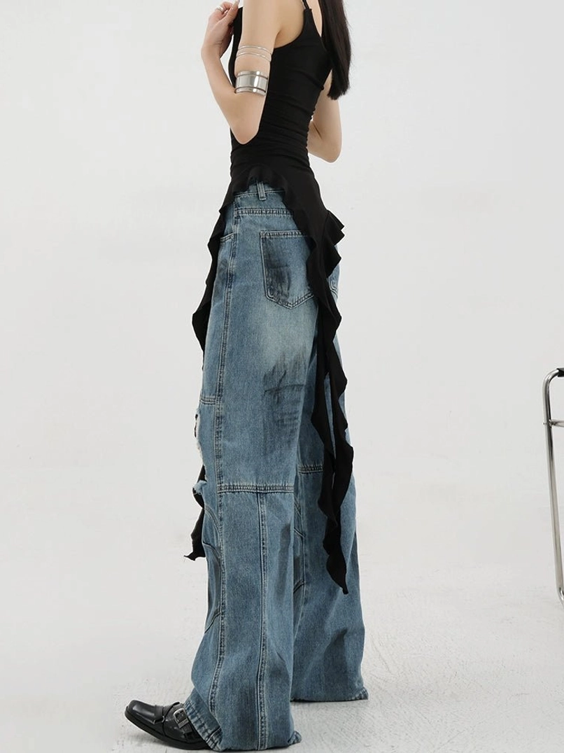 Vintage distressed wide-leg jeans left full side view on female model with black asymmetric camisole showing classic denim back pocket faded blue wash loose wide leg fit ripped knee details