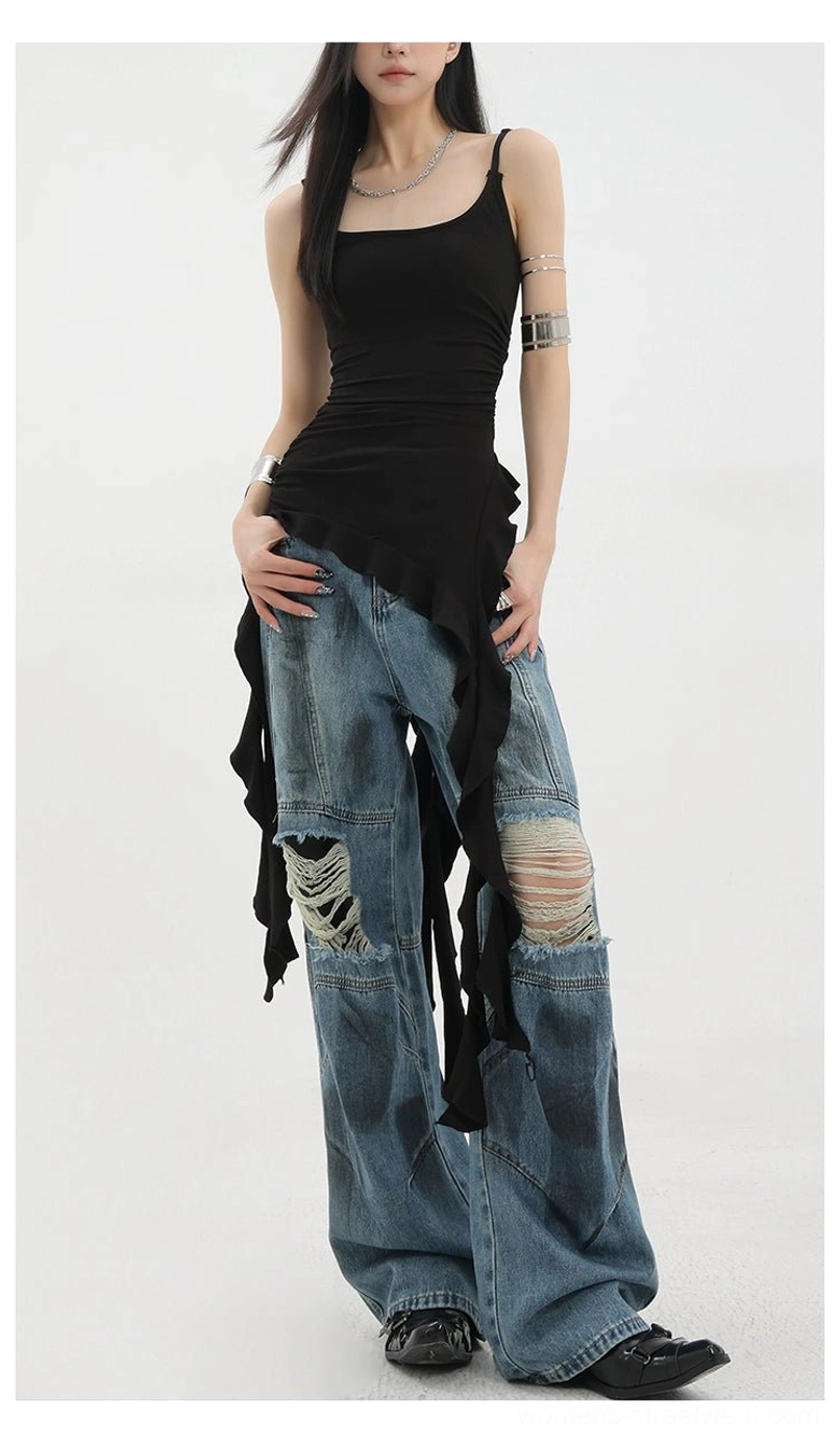 Vintage distressed wide-leg jeans standard front view on female model with black asymmetric camisole showing ripped knee destruction dirt-dyed blue denim finish wide leg pants white studio background
