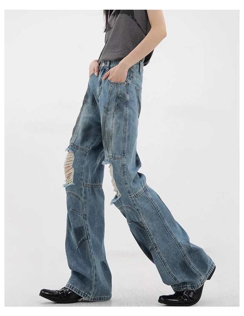 Vintage distressed wide-leg jeans thigh area close-up showing faded blue wash dirt-dyed texture and ripped detail placement characteristic of intentional distressed design