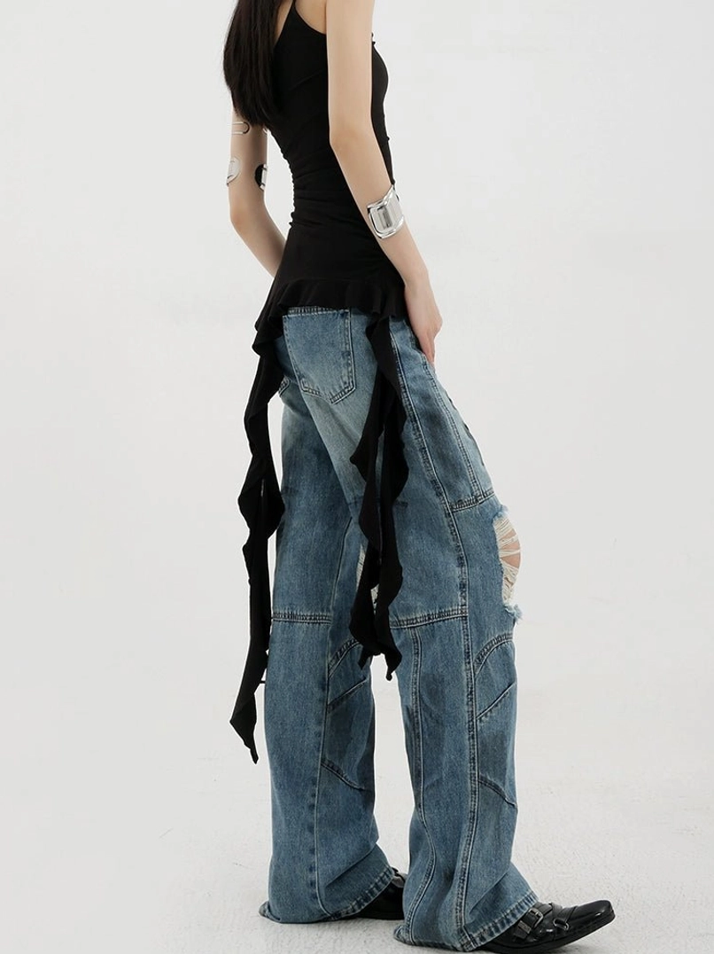 Vintage distressed wide-leg jeans right three-quarter side view on female model wearing black asymmetric camisole visible ripped knee details faded denim texture wide leg cut paneled garment construction