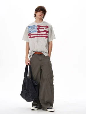 Full body styling of a faded grey oversized vintage flag T-shirt with wide leg cargo pants brown belt and black canvas tote bag