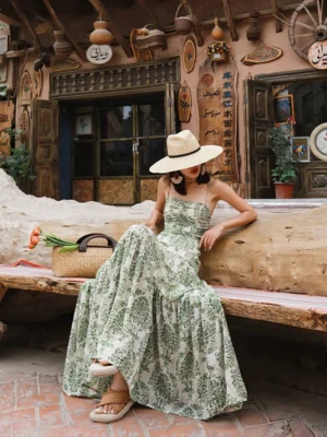 Vintage green floral tie-back tiered maxi dress worn in a seated front view with ruched bodice and spaghetti straps