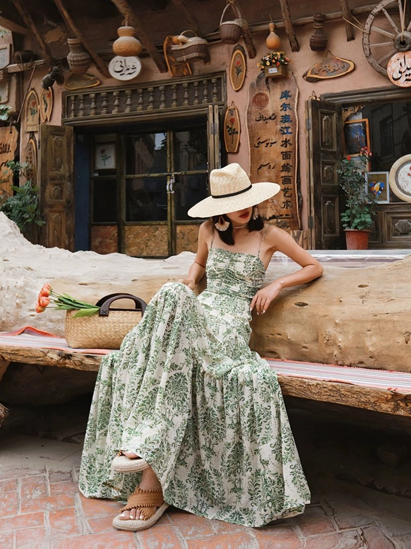 Vintage green floral tie-back tiered maxi dress worn in a seated front view with ruched bodice and spaghetti straps
