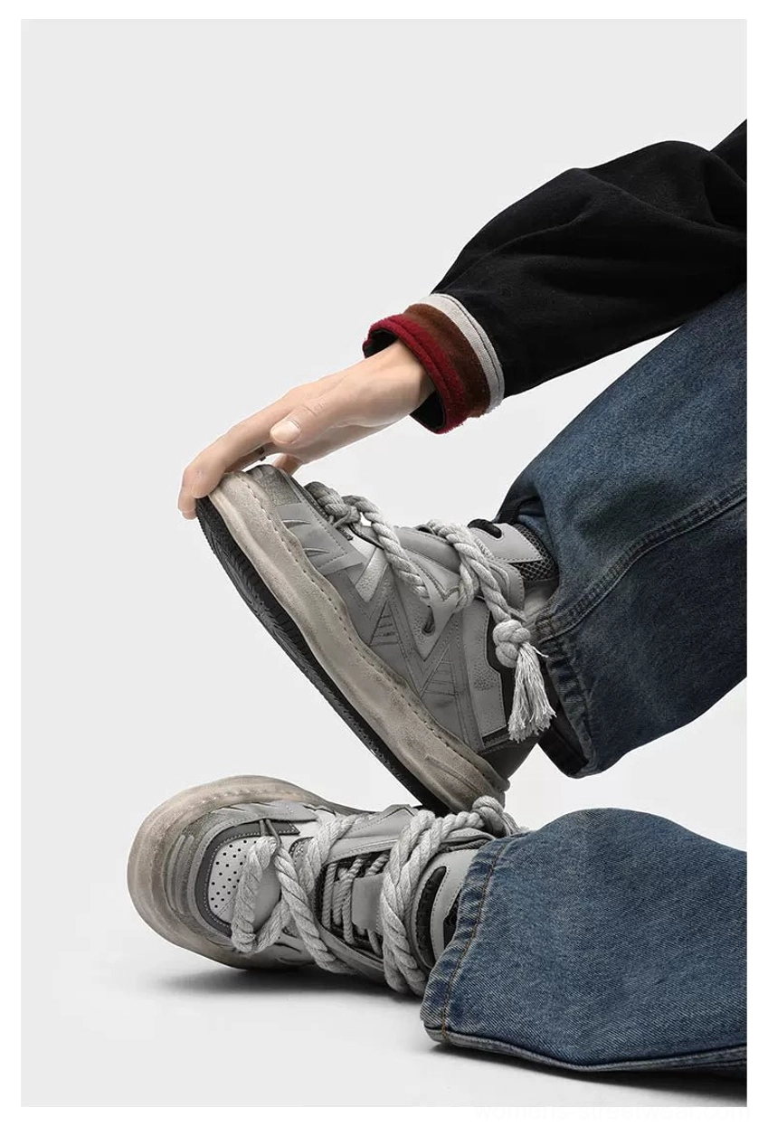 Close-up view of vintage grey distressed chunky sneakers styled with blue denim jeans, twisted rope laces, textured worn soles, and casual Korean streetwear attitude