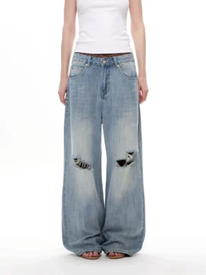 Front view of vintage light blue distressed wide-leg jeans with oversized balloon silhouette and frayed knee details