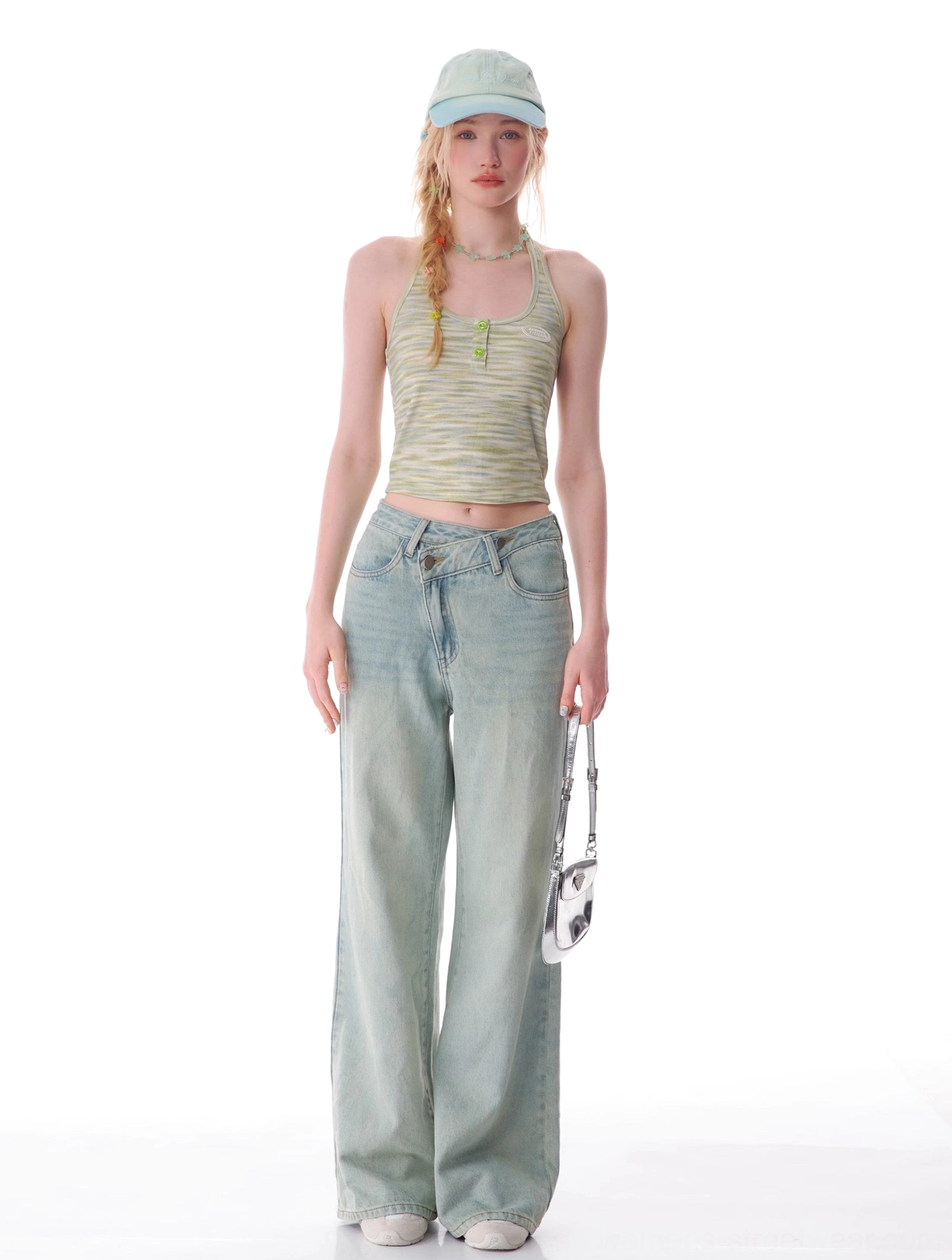 Front streetwear styling of vintage light blue wide leg jeans with cropped halter top, cap, and metallic handbag