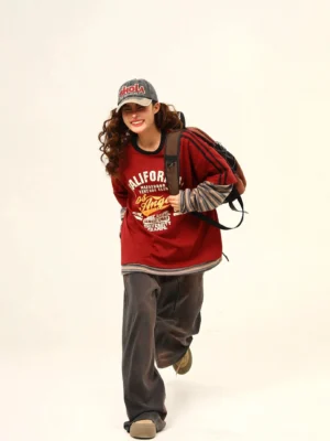 Oversized burgundy Los Angeles varsity graphic tee with faux layered striped sleeves in streetwear outfit