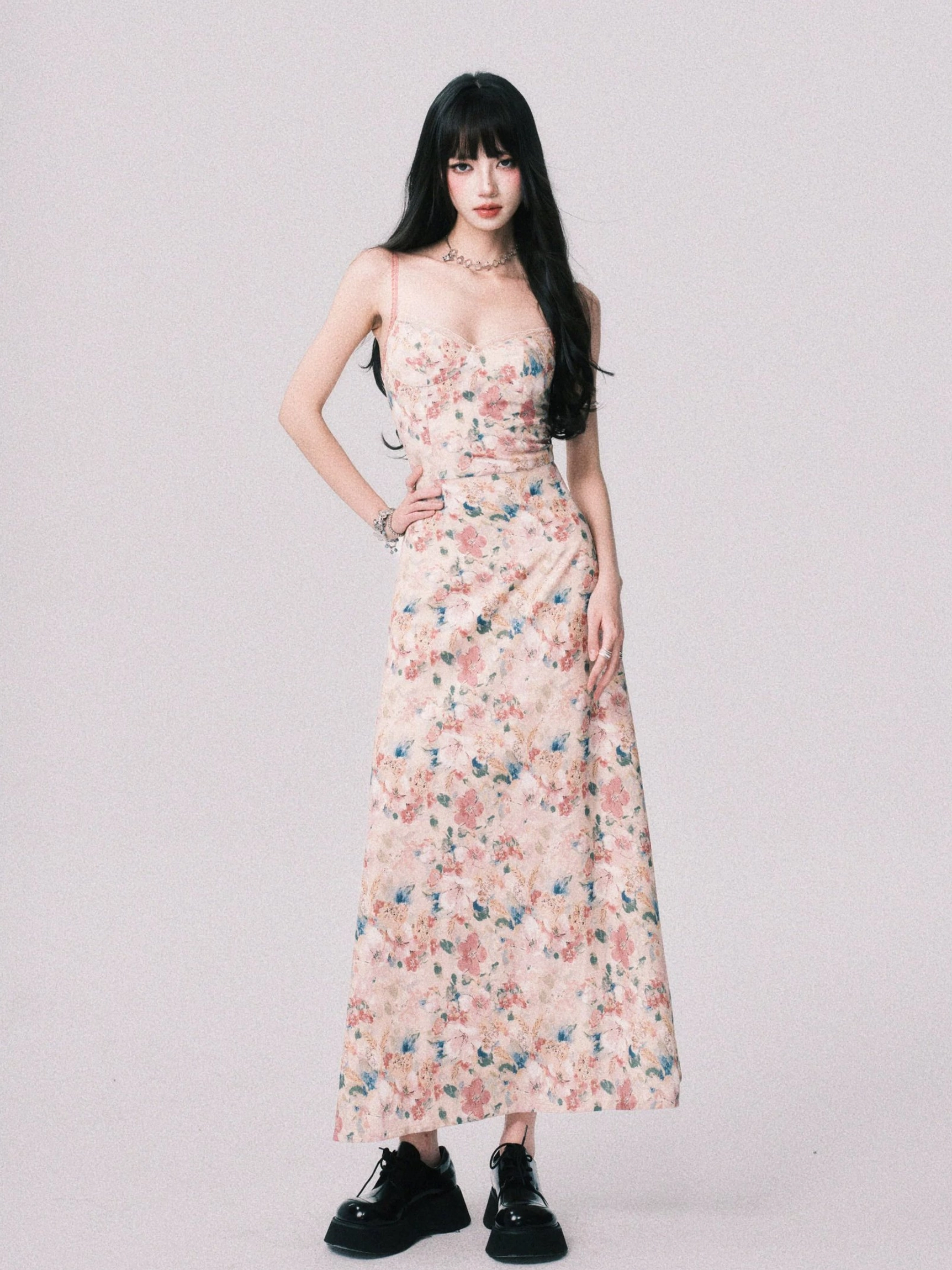Side front view of a vintage inspired floral spaghetti strap maxi dress with fitted bodice, ankle length flowing skirt, platform loafers, and bracelet
