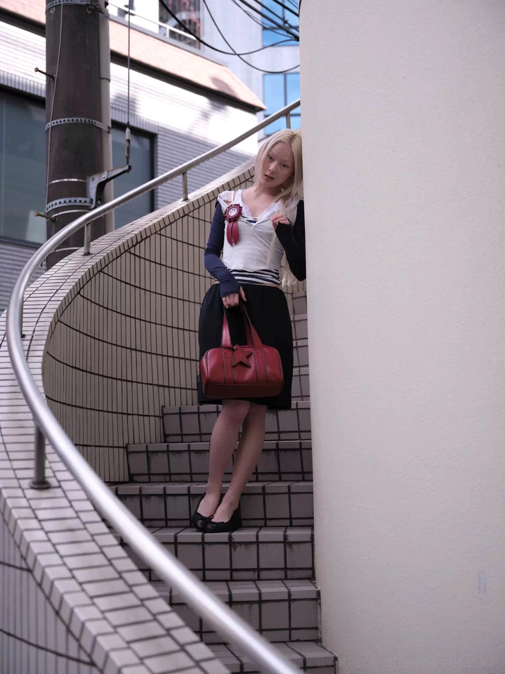 Deep crimson red vintage star east-west bowling handbag worn in an urban street style setting near tiled stairs