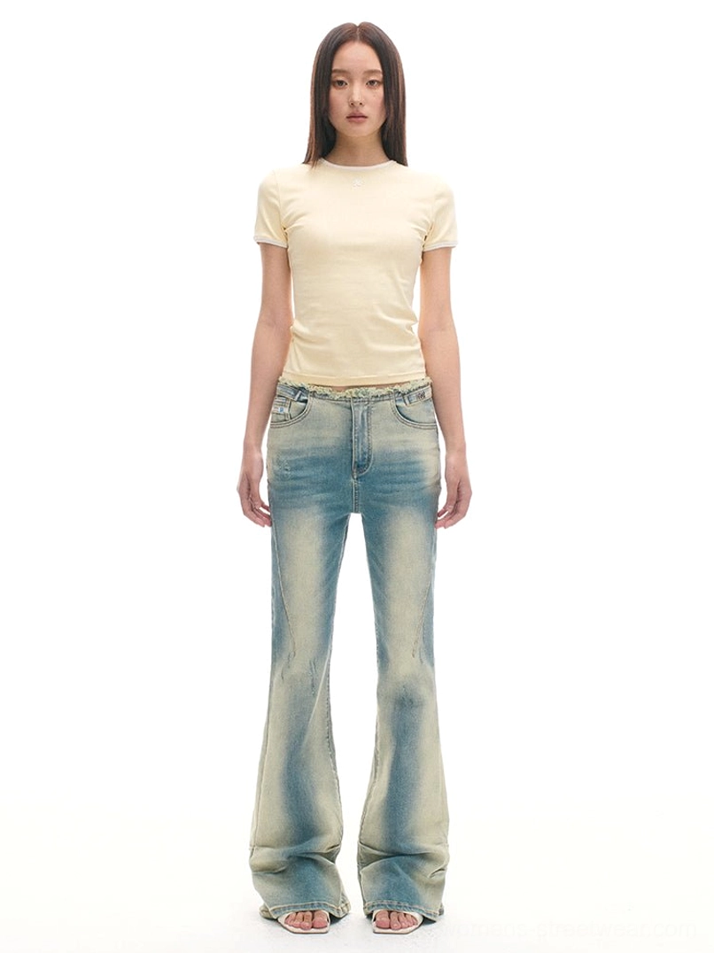 Vintage wash blue flared denim jeans styled with a cream T-shirt in a full-length streetwear outfit