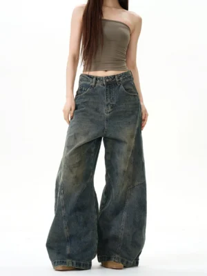 Front full-body view of retro blue vintage wash extreme wide-leg jeans styled with a khaki strapless top in a modern streetwear outfit