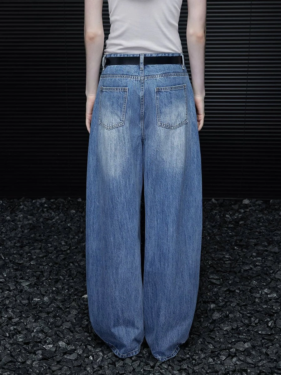 Back full body view of women’s washed blue barrel leg jeans with rear pockets, faded denim finish, and relaxed silhouette
