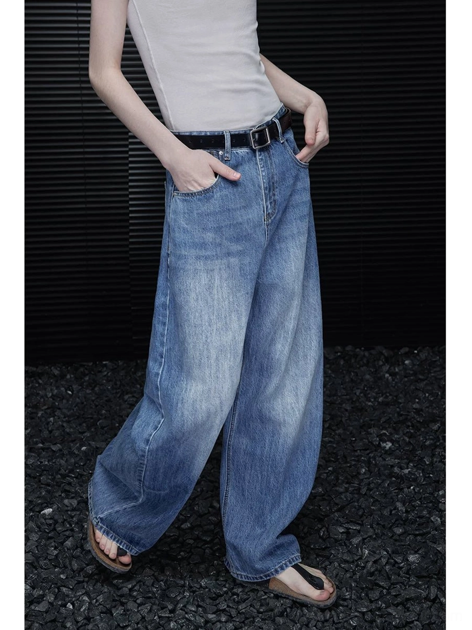 Three quarter front detail of washed blue barrel leg denim jeans with classic front pockets and relaxed streetwear fit