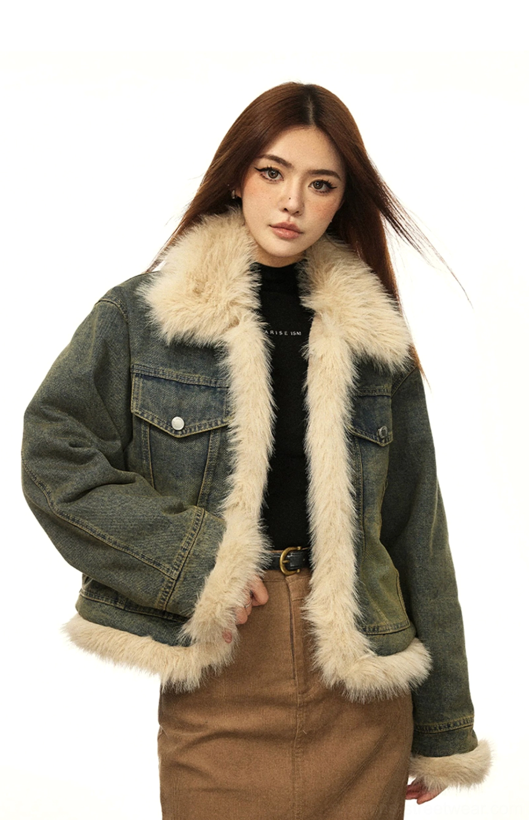 Front view of a woman wearing a vintage washed blue denim jacket with beige faux fur trim black turtleneck and brown leather belt