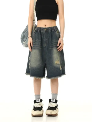 Front view of vintage washed blue distressed denim Bermuda shorts with ripped details, wide-leg fit, pressed creases, and frayed hems