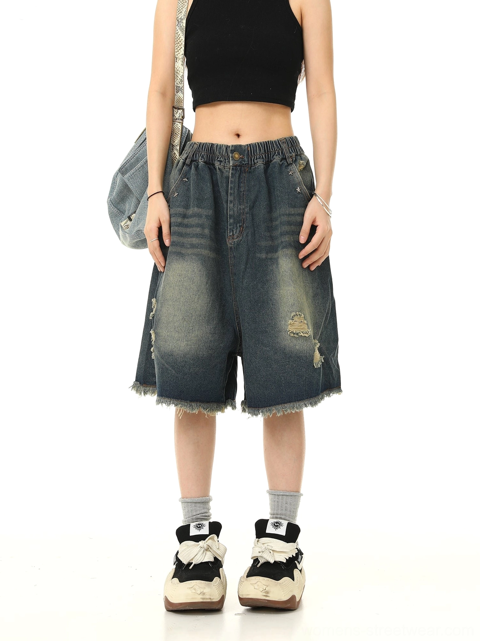 Front view of vintage washed blue distressed denim Bermuda shorts with ripped details, wide-leg fit, pressed creases, and frayed hems