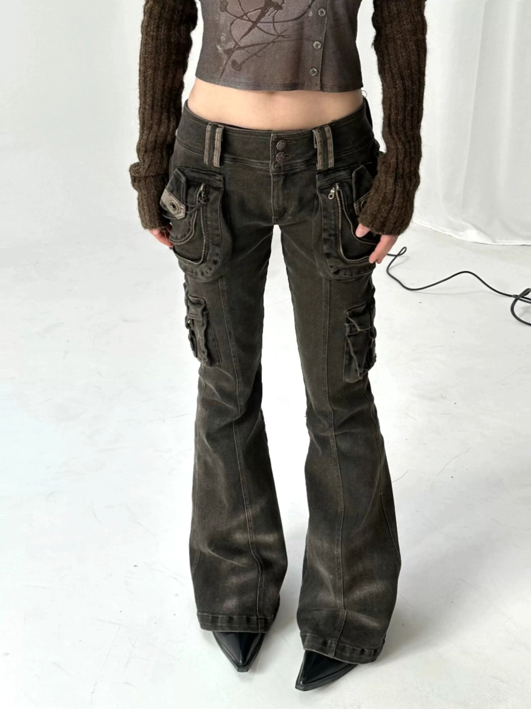 Front lower-body view of vintage washed cargo flare jeans with double belt loops, front utility pockets, faded dark denim, and pointed boots