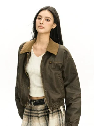 Dark brown vintage washed cropped bomber jacket with contrasting corduroy collar, chest zipper pocket, snap cuffs, and elasticated hem shown from a three quarter front view