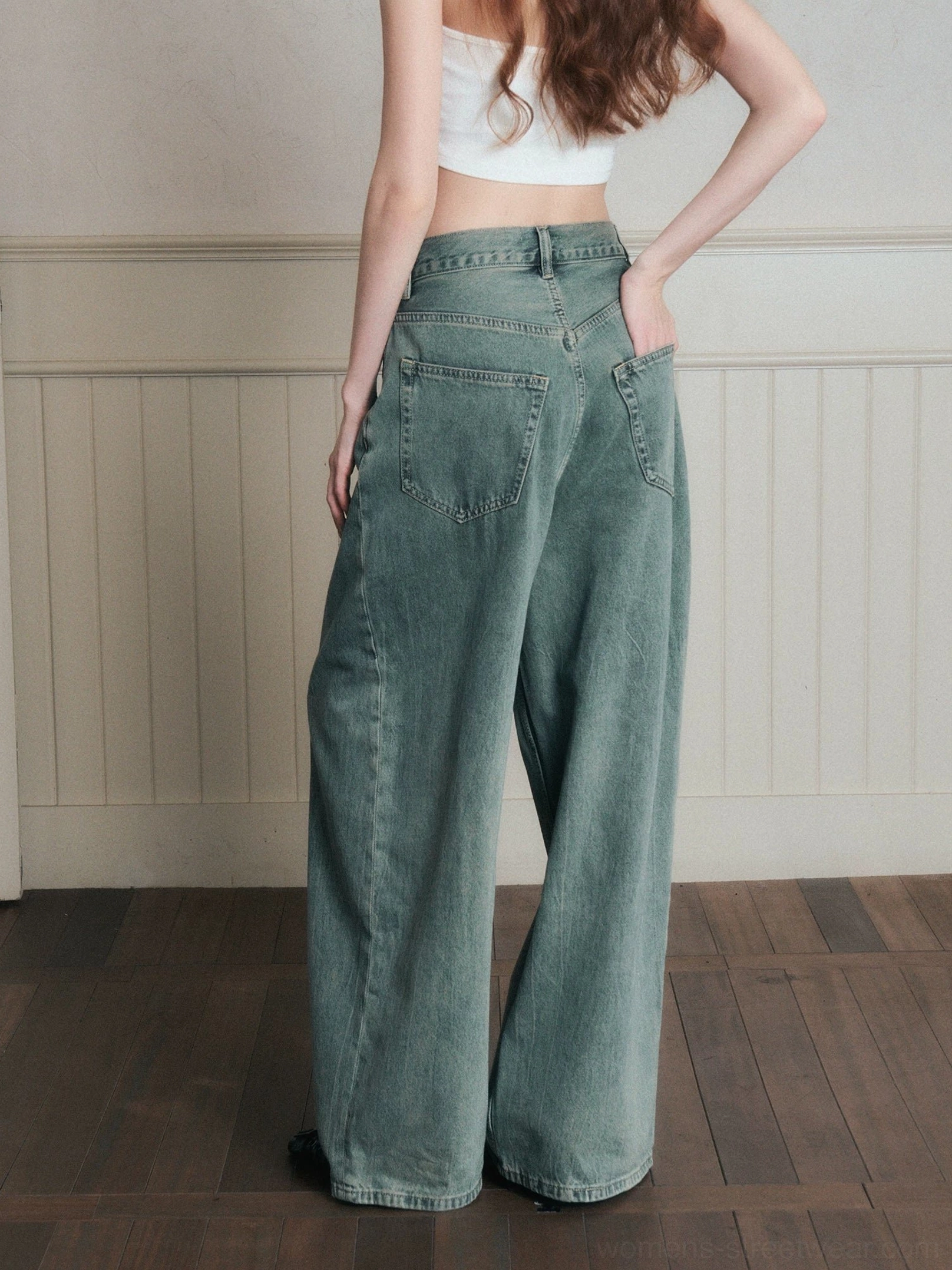Back view of women wearing vintage sage blue wide-leg jeans with a cropped white tank top, showing the relaxed streetwear fit and full-length denim silhouette