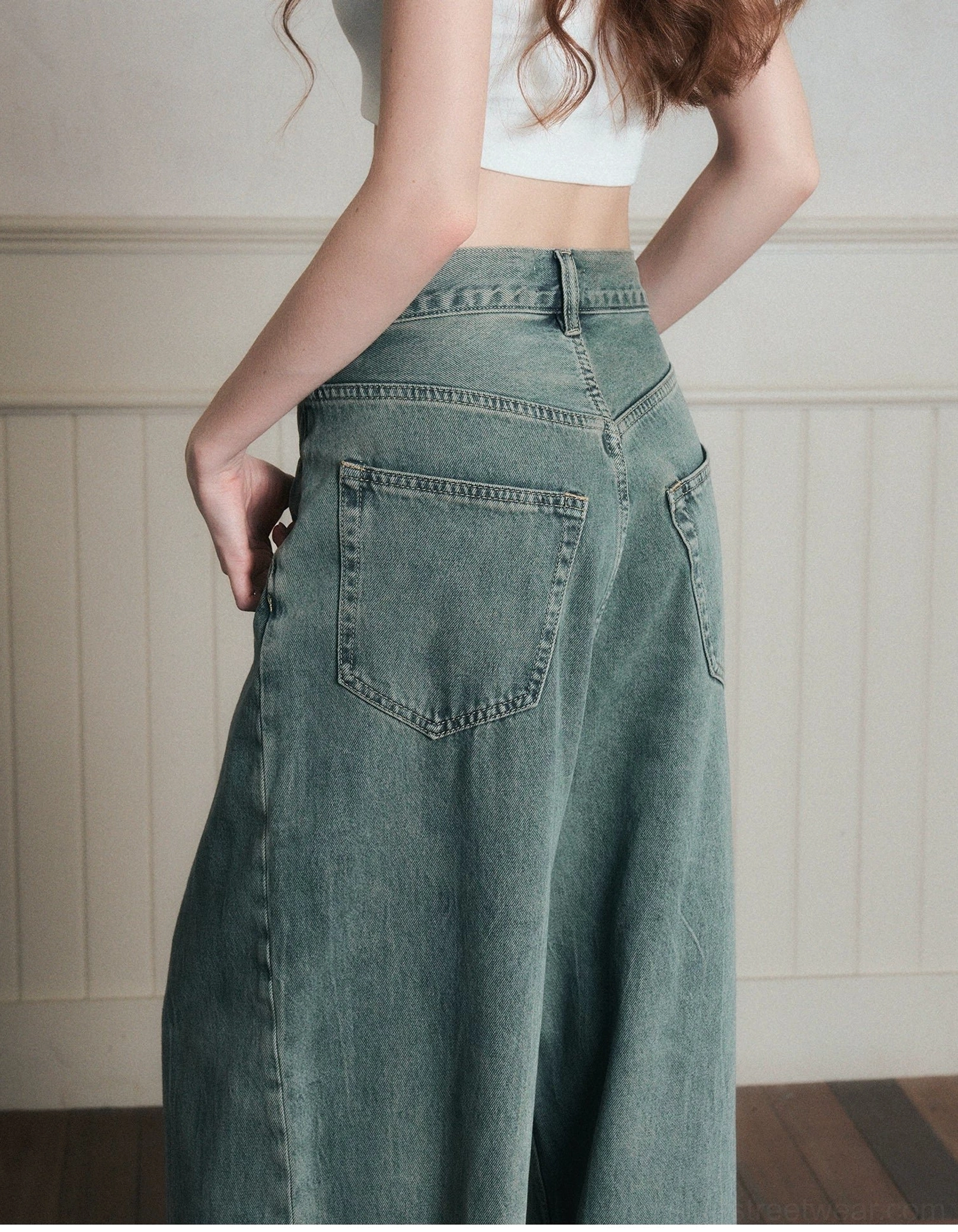 Close-up back view of vintage washed wide-leg jeans showing stitched classic denim pockets, belt loops, and natural faded cotton texture