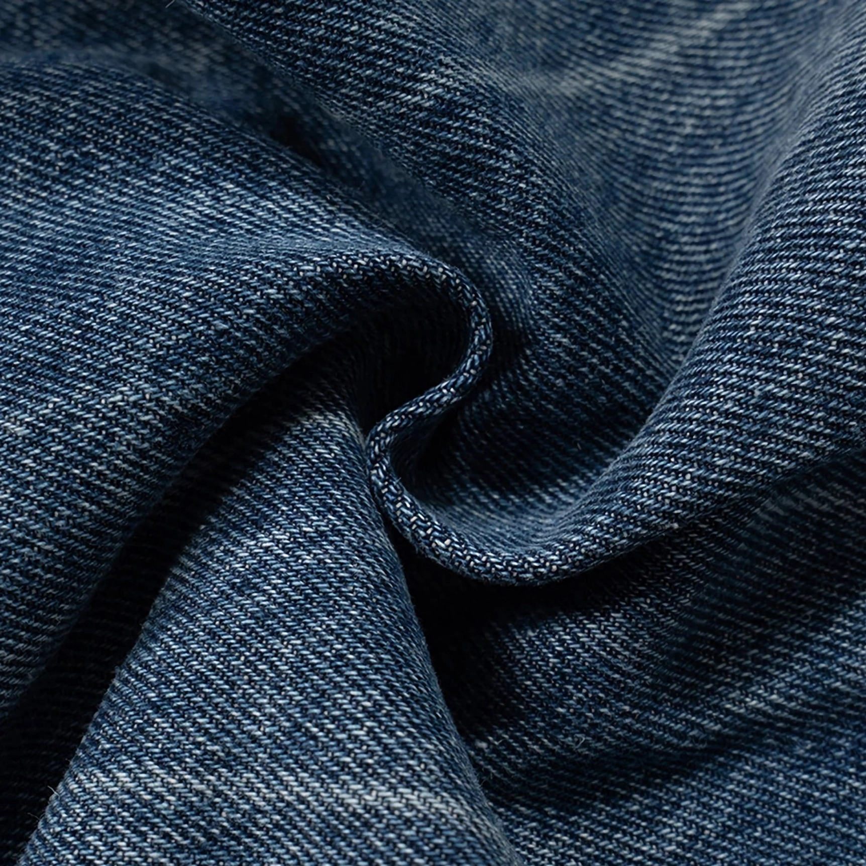 Close-up draped view of cotton twill denim fabric from vintage wide-leg streetwear jeans showing soft creases and natural faded coloring
