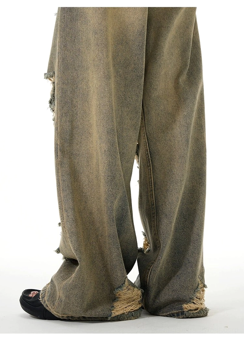 Close-up back view showing the vintage yellow-washed denim, wide legs, frayed raw hems, and unfinished edges