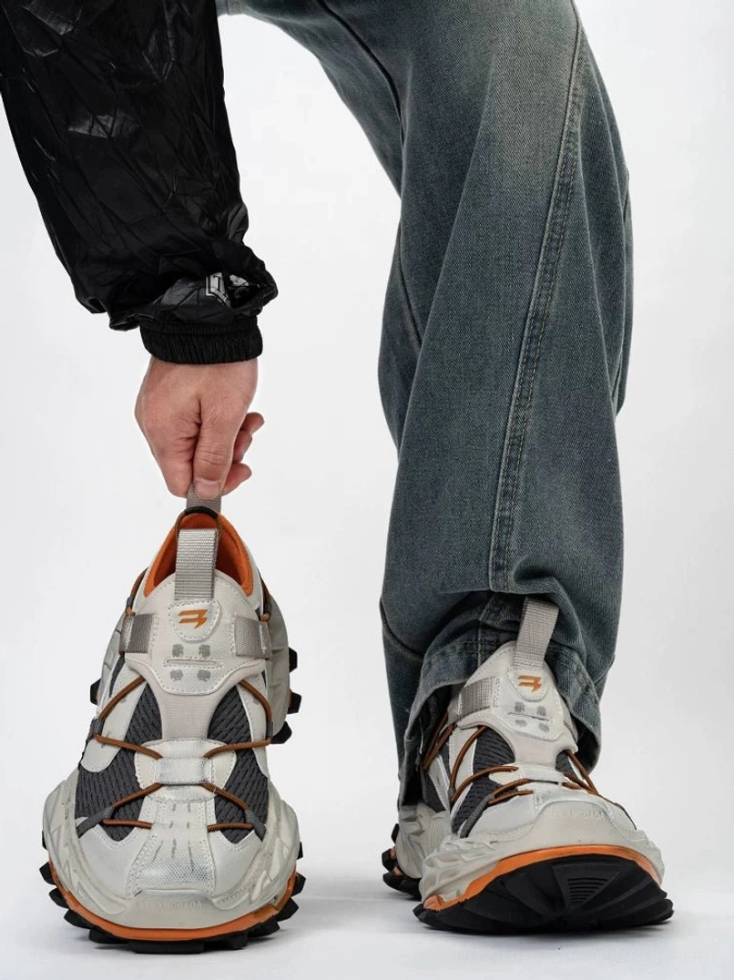 Grey orange and black chunky techwear sneakers shown from the front and side with contrast panels, sculpted rubber sole, breathable upper, and futuristic urban streetwear design