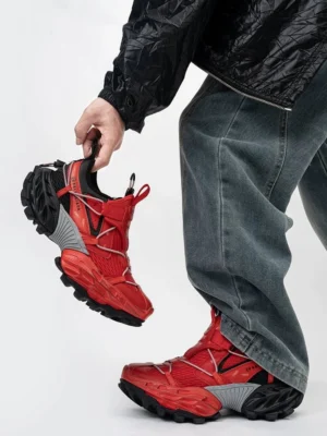 Red black and grey tech trail sneakers featuring a bold red mesh upper, grey heel counter, utility strap details, and deep anti-slip lugged rubber outsole for gorpcore streetwear styling