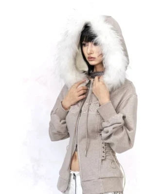 Warm gray fur trim lace-up zip hoodie in a three-quarter front full-body studio view, featuring a plush white hood border, tonal chest embroidery, ribbed hem, and corset-style side waist lacing