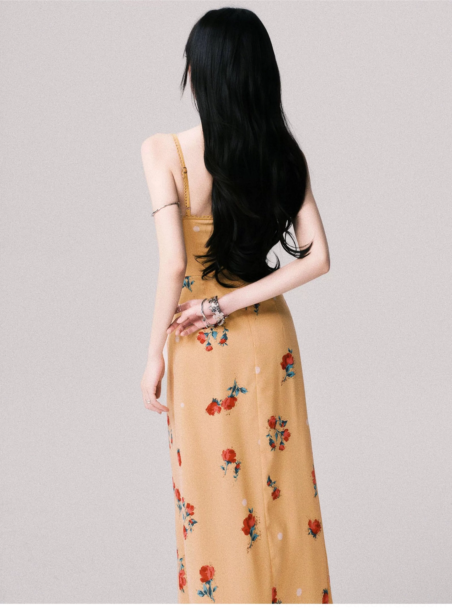 Back view of a warm yellow floral camisole maxi dress with open back slender straps and long printed skirt