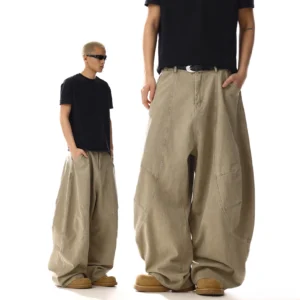Washed barrel-leg utility pants in a khaki-inspired streetwear silhouette shown from the side and front three-quarter view with curved seams and oversized utility pockets