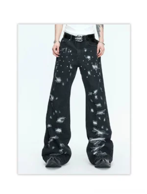 Front view of washed black distressed wide-leg jeans with large ripped openings, scattered silver studs, and relaxed draped streetwear fit