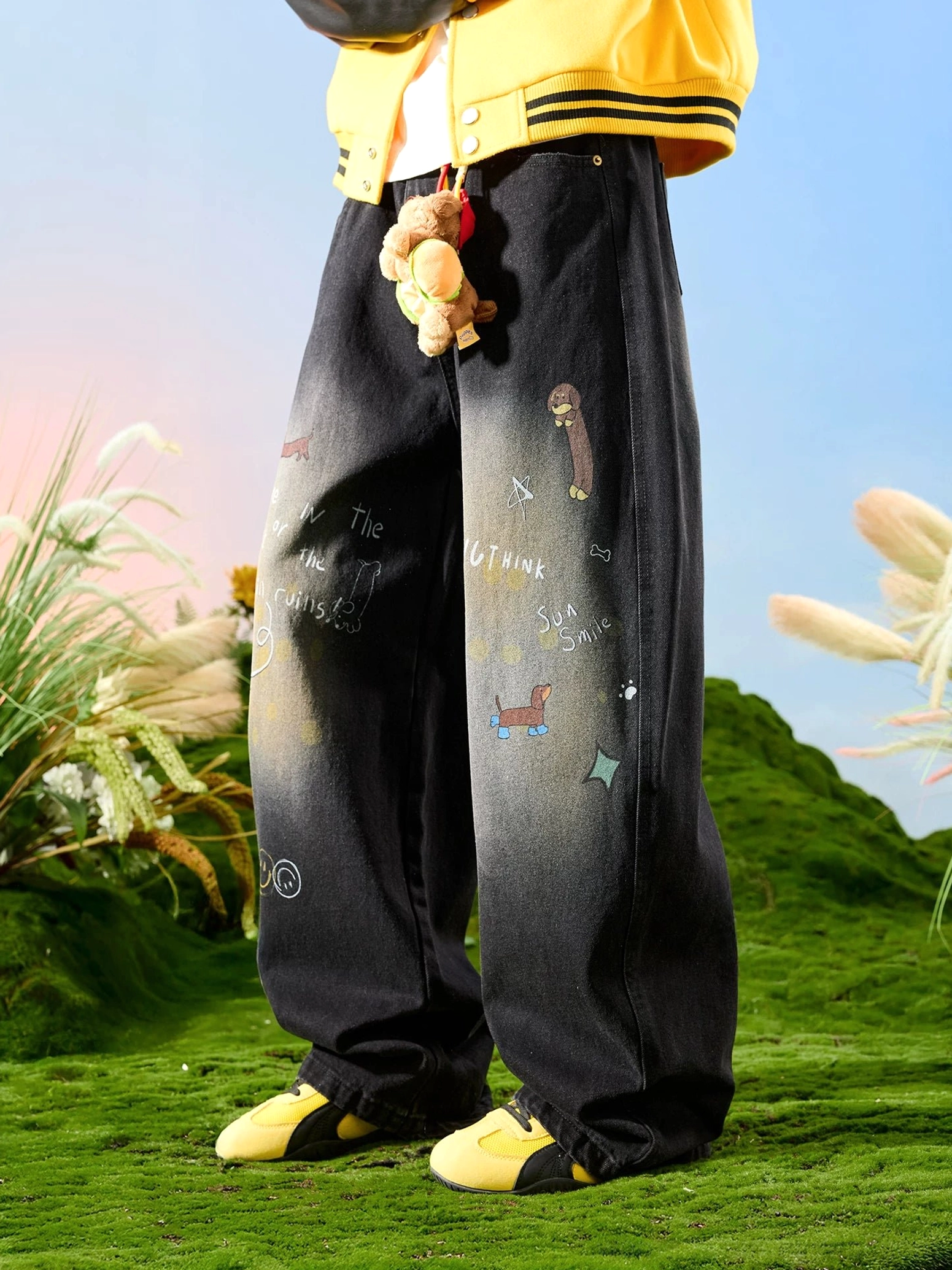 Side view of washed black wide leg doodle jeans featuring teddy bear plush pendant assorted cute graphics and relaxed denim fit
