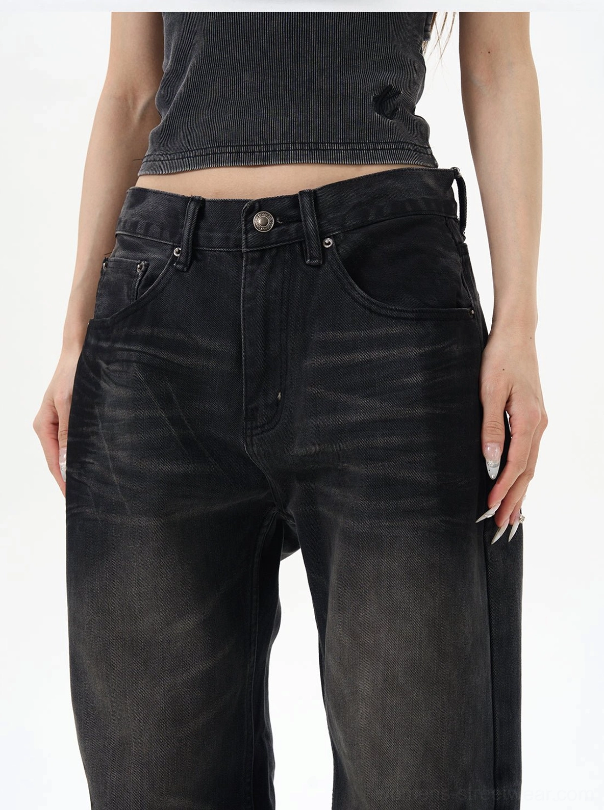 Close-up of the washed black loose jeans waistband showing button fly, belt loops, precise stitching, and structured non-stretch denim